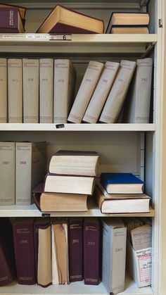 several books are stacked on top of each other in a bookcase with no doors