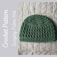 a green crocheted hat sitting on top of a bed next to a blanket