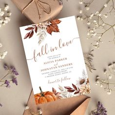 a wedding card with fall leaves and pumpkins on it, next to some flowers