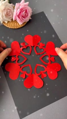 someone is cutting out hearts on a piece of paper to make a snowflake