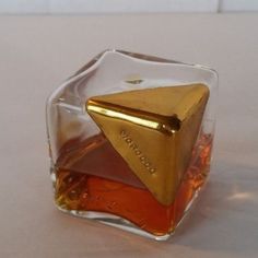 a small glass bottle with some liquid in it and a gold triangle on the top