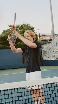 a young man holding a tennis racquet on top of a tennis ball court