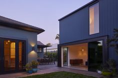 a house that has some lights on in the back yard and patio area with chairs around it