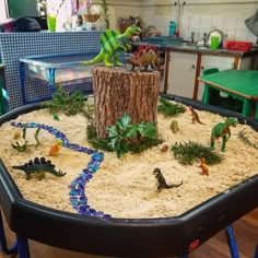 a play table with toys and sand in the shape of a tree stump on it