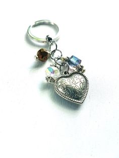 a silver heart shaped keychain with an elephant on it's side and a crystal bead charm hanging from the front