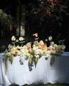 the table is covered with white linens and flowers