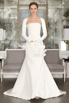 a woman in a white wedding dress standing next to a couch with flowers on it