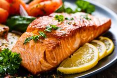 salmon and vegetables on a plate with lemon wedges