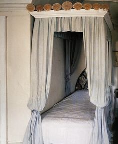 a four poster bed with blue drapes and pillows on the headboard is shown