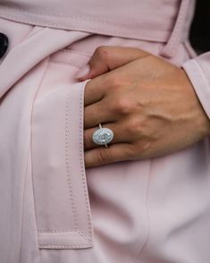 a close up of a person wearing a pink coat with a ring on their finger