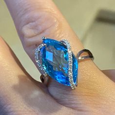 a woman's engagement ring with an aqua blue stone and diamond accents on it