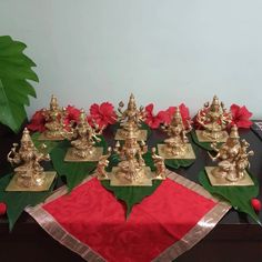 a table topped with lots of gold figurines on top of red napkins