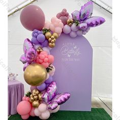 a balloon arch decorated with balloons and streamers for a little butterfly 1st birthday party