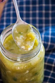 a spoon full of green enchilada sauce on top of a mason jar