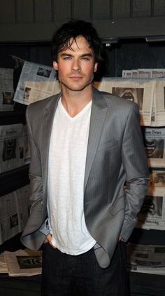 a man standing in front of a wall full of newspapers