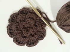 a crochet flower with two knitting needles next to it