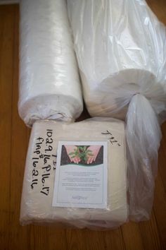 two rolls of toilet paper sitting on top of a wooden floor next to plastic bags