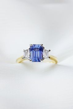 a blue and white diamond ring with three baguettes on it's side