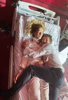 two people laying in a hospital bed with their arms around each other as they hug