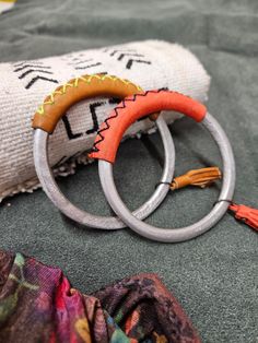 two metal rings with tassels on top of a blanket next to a pillow