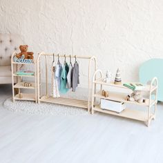 a baby's clothing rack in the corner of a room next to a teddy bear