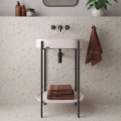 a white sink sitting under a bathroom mirror next to a towel rack and potted plant