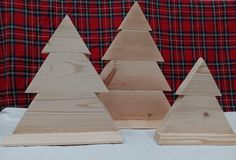 three wooden christmas trees on a white tablecloth with red and black plaid fabric in the background