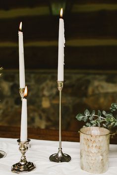 three candles sitting on top of a white table cloth