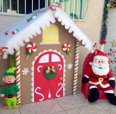 an outdoor christmas decoration with santa and elf figures in front of a gingerbread house