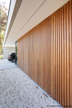 a car is parked in front of a building with wood slats on the side