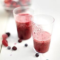 two glasses filled with berry smoothie on top of a table