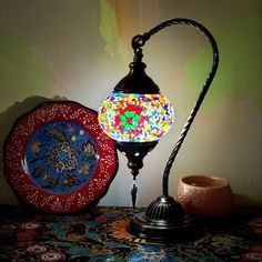 a colorful lamp sitting on top of a table next to a bowl and plate holder