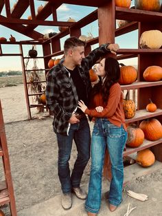 a man and woman standing next to each other near pumpkins on shelves in the desert