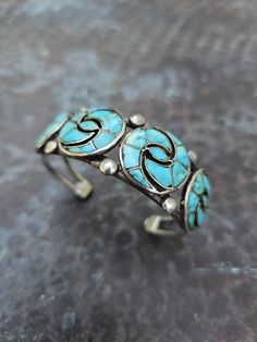 This beautiful cuff has a well-known inlay pattern that was originally created by Ellen Quandelacy. It is unsigned but features natural turquoise on a pulled wire shank. This piece has seen many decades of love and has an old repair to a backside wire, but is unnoticeable from the top of the cuff. c. 1950s Internal Circumference: 5 3/8" not including gap of 1 1/8" Height: 3/4" Weight: 37g Vintage Turquoise Bracelets With Inlay, Vintage Turquoise Bracelet With Inlay, Adjustable Turquoise Bracelet With Inlay, Adjustable Turquoise Inlay Bracelets, Unique Adjustable Inlay Cuff Bracelet, Bohemian Turquoise Inlay Cuff Bracelet, Bohemian Adjustable Cuff Bracelet With Inlay, Inlay Pattern, Turquoise Jewelry Native American