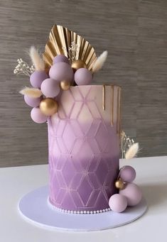 a purple cake with gold decorations and feathers on top is sitting on a white plate