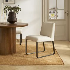 a dining room with a table and chair next to a potted plant on the floor