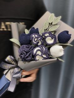 a woman holding a bouquet of crocheted flowers