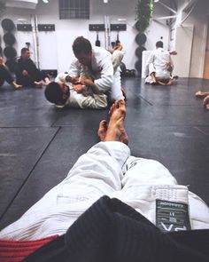 a group of men sitting on the ground in a gym with one man holding his leg up