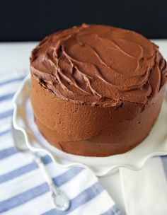 a chocolate cake sitting on top of a white plate next to a blue and white napkin