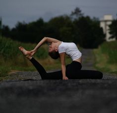 a woman is doing yoga on the road