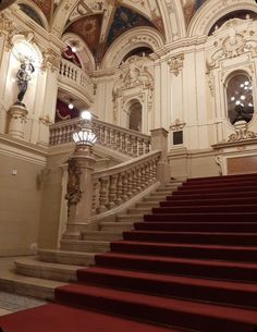 an ornate staircase with red carpet and white walls