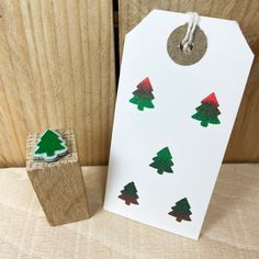 a wooden stamp with christmas trees on it next to a white tag and wood block