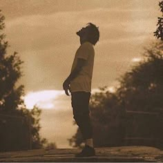 a man standing on top of a skateboard under a cloudy sky