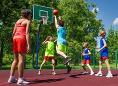 young children playing basketball on an outdoor court