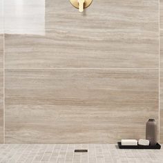 a modern bathroom with beige tile and gold fixtures on the wall, along with a black soap dispenser