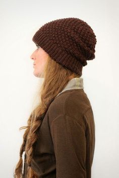 a woman with long hair wearing a brown knitted beanie and looking off to the side