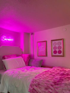 a bedroom with pink lights and a bed in the middle is lit up by two framed pictures