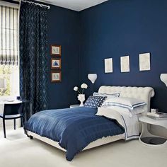 a bedroom with blue walls and white bedding, along with pictures on the wall