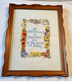 an embroidered frame with flowers and the words, all the flowers of tomorrow in the seeds of today