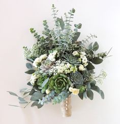 a bridal bouquet with succulents and greenery on a white wall